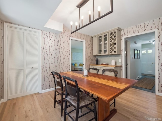 dining room with wallpapered walls, light wood-style floors, and baseboards