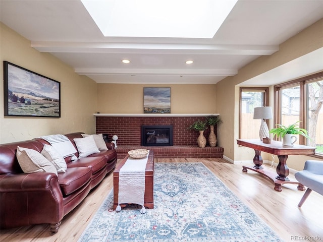 living area with beamed ceiling, a skylight, wood finished floors, recessed lighting, and a brick fireplace