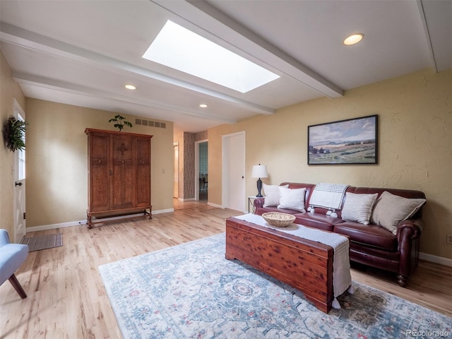 living area featuring a skylight, light wood-type flooring, beam ceiling, baseboards, and recessed lighting