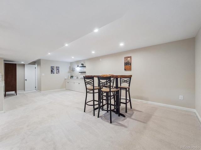 dining space featuring wet bar, light colored carpet, baseboards, and recessed lighting