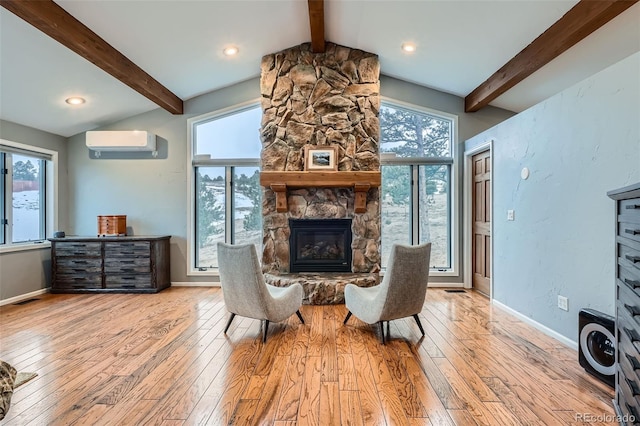 sitting room with light hardwood / wood-style floors, vaulted ceiling with beams, a wall unit AC, and a fireplace