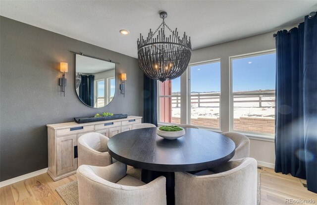 8576 Hotchkiss St, Littleton, CO 80125 - dining area with light wood-type flooring, baseboards, and an inviting chandelier