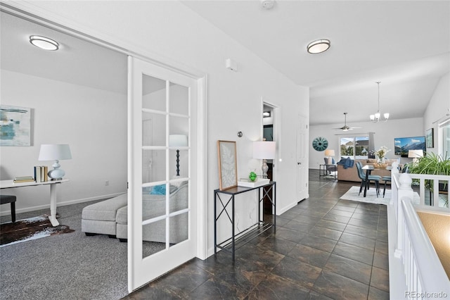 hall with vaulted ceiling, baseboards, and a notable chandelier