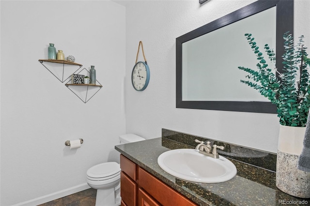 bathroom featuring vanity, toilet, and baseboards