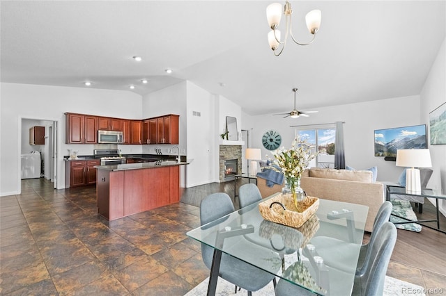 dining space featuring baseboards, visible vents, lofted ceiling, a stone fireplace, and ceiling fan with notable chandelier