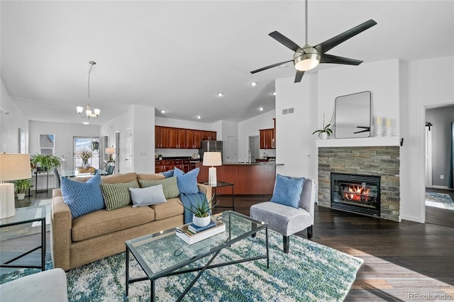 living room with a stone fireplace, ceiling fan with notable chandelier, lofted ceiling, and dark hardwood / wood-style flooring