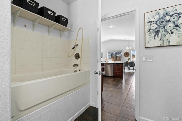 bathroom with tiled shower / bath combo, vaulted ceiling, a textured ceiling, and a notable chandelier