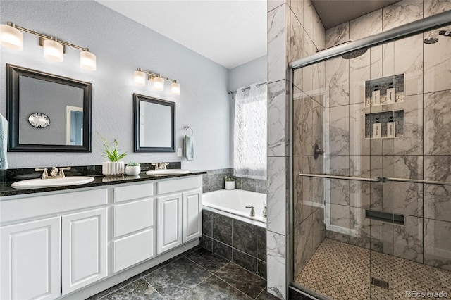 bathroom with a garden tub, a sink, a shower stall, and double vanity