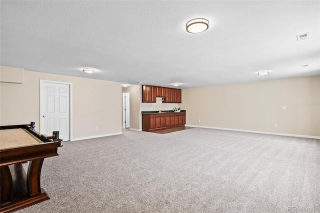 interior space featuring carpet, visible vents, a textured ceiling, and baseboards