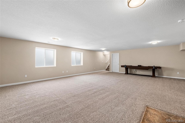 below grade area with a textured ceiling, stairway, carpet, and baseboards