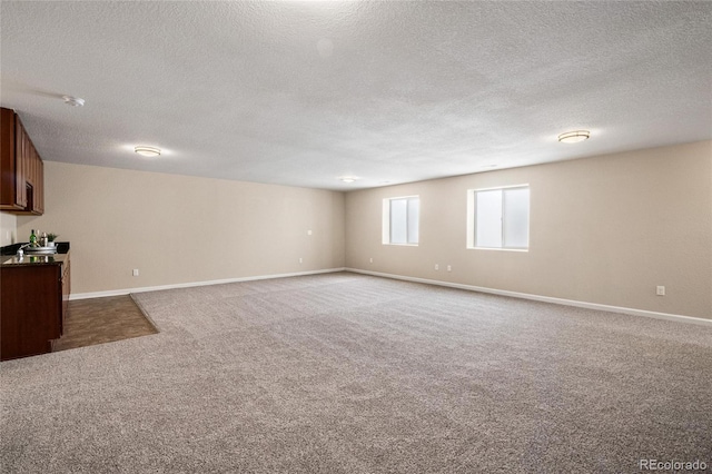 interior space featuring dark carpet, a textured ceiling, and baseboards