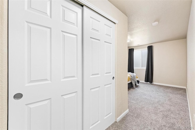 hall featuring carpet flooring, a textured ceiling, and baseboards