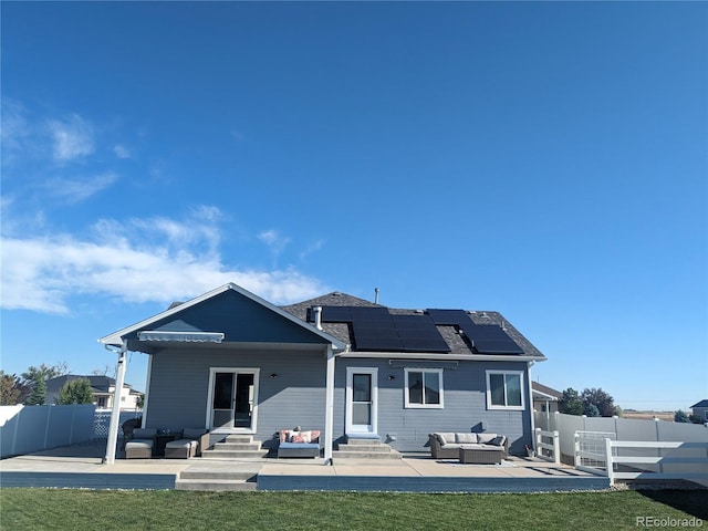 back of house with an outdoor living space, a patio, a lawn, and solar panels