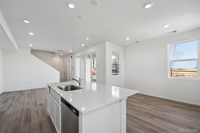 kitchen with white cabinetry, dishwasher, sink, a center island with sink, and light hardwood / wood-style flooring