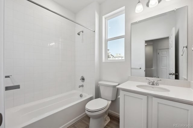 full bathroom featuring tiled shower / bath, vanity, toilet, and wood-type flooring