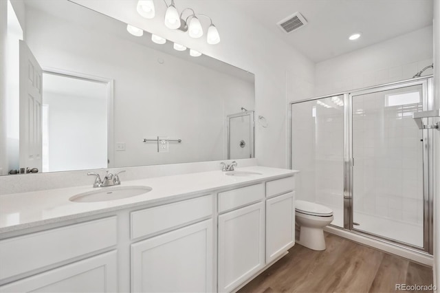 bathroom with hardwood / wood-style flooring, vanity, a shower with door, and toilet