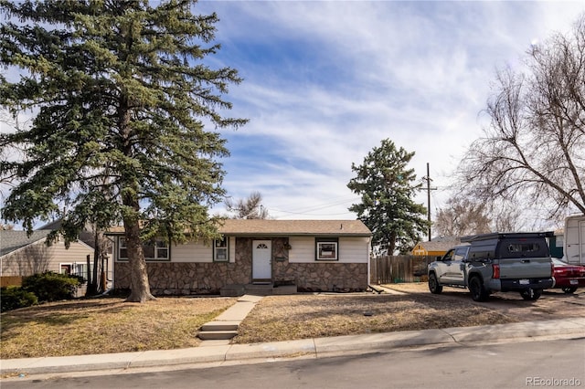 ranch-style house with stone siding and fence