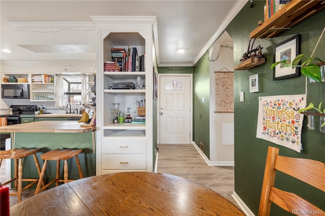 kitchen featuring black appliances, light wood-style flooring, ornamental molding, open shelves, and wooden counters