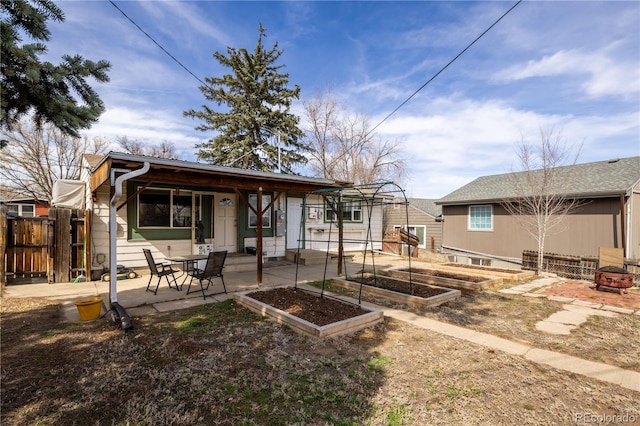 back of property with a patio area, a vegetable garden, and fence