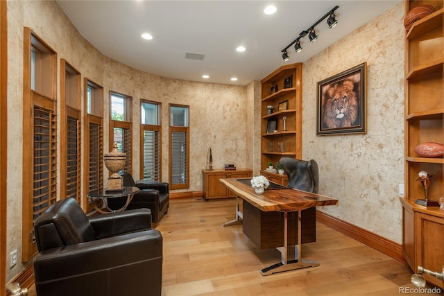 home office with track lighting and light hardwood / wood-style floors