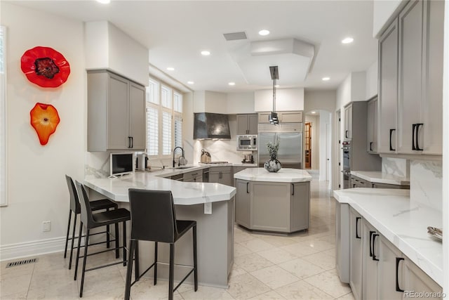 kitchen with gray cabinets, a kitchen island, hanging light fixtures, and built in appliances