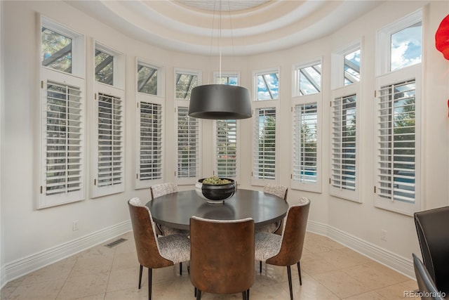 dining room featuring a tray ceiling, a towering ceiling, and light tile patterned floors