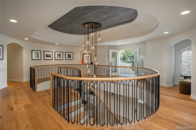 hallway featuring a tray ceiling and light hardwood / wood-style flooring