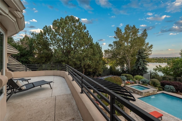 balcony featuring a water view, a patio, an in ground hot tub, and pool water feature