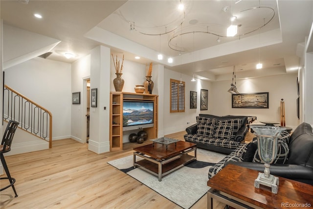 living room featuring light wood-type flooring and a tray ceiling