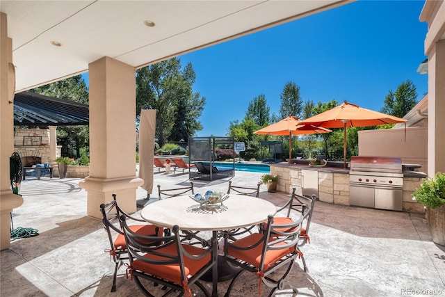 view of patio / terrace featuring exterior kitchen, a fenced in pool, an outdoor stone fireplace, and grilling area