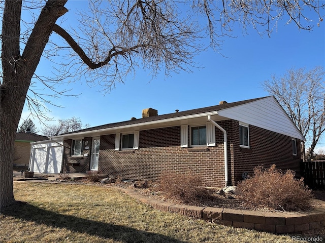 ranch-style home with a garage, a chimney, a front lawn, and brick siding