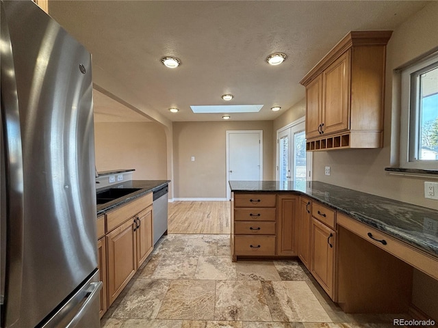 kitchen featuring a peninsula, a skylight, a healthy amount of sunlight, and appliances with stainless steel finishes