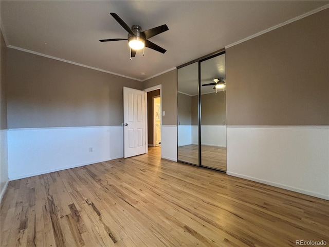 unfurnished bedroom with crown molding, a closet, ceiling fan, wood finished floors, and baseboards