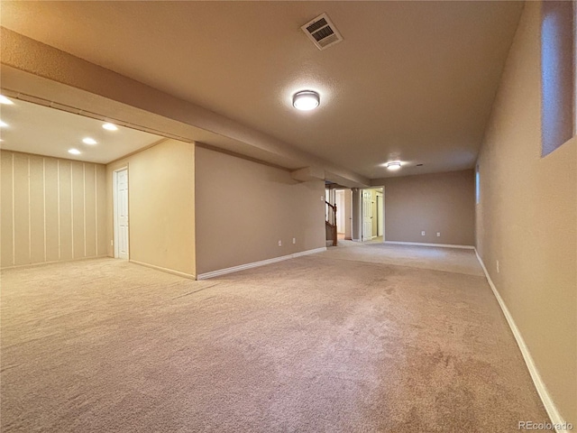 finished below grade area featuring stairway, carpet, visible vents, and baseboards