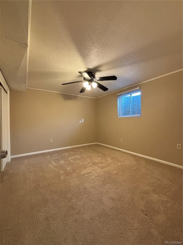 carpeted spare room with a textured ceiling, a ceiling fan, and baseboards