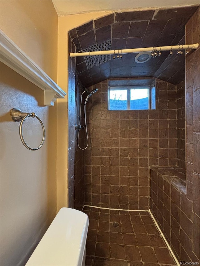 full bath featuring tiled shower and toilet