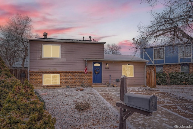 view of front facade featuring fence, a patio, and brick siding