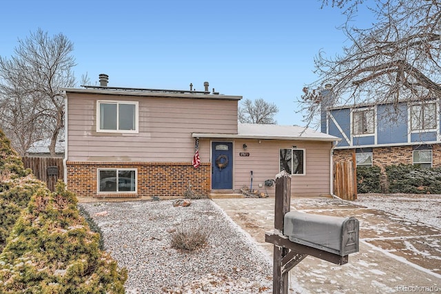 view of front of house featuring fence and brick siding