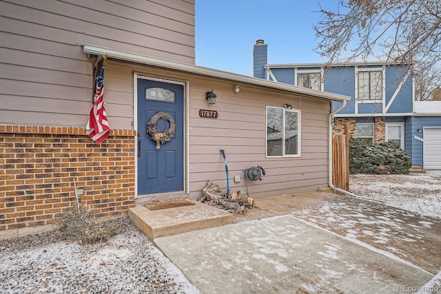 doorway to property featuring brick siding and a chimney