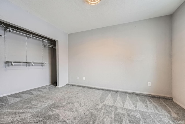 unfurnished bedroom with a textured ceiling, carpet floors, a closet, and baseboards