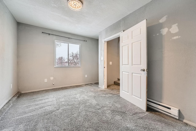 unfurnished bedroom featuring carpet floors, baseboards, baseboard heating, and a textured ceiling