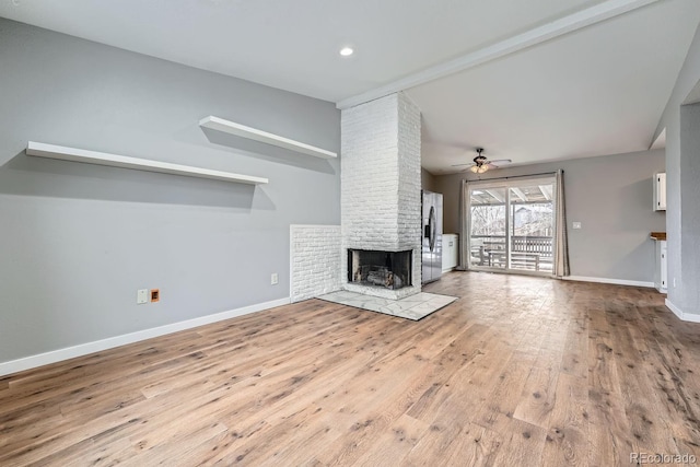 unfurnished living room with a brick fireplace, vaulted ceiling, baseboards, and ceiling fan