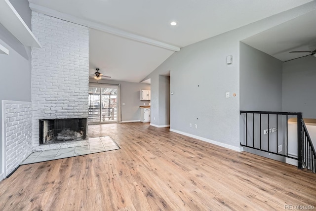 unfurnished living room featuring baseboards, a ceiling fan, lofted ceiling with beams, wood finished floors, and a fireplace