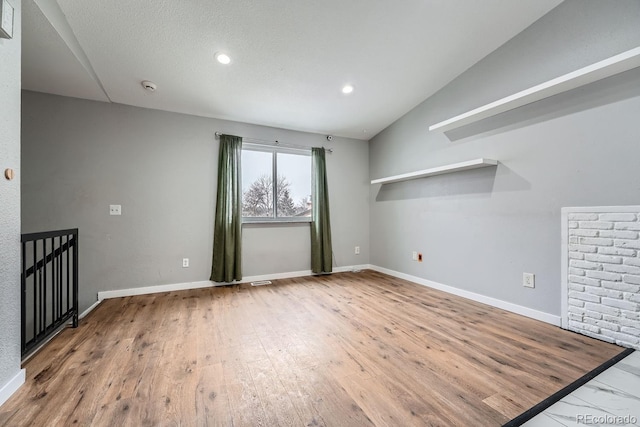 spare room featuring lofted ceiling, recessed lighting, wood finished floors, and baseboards