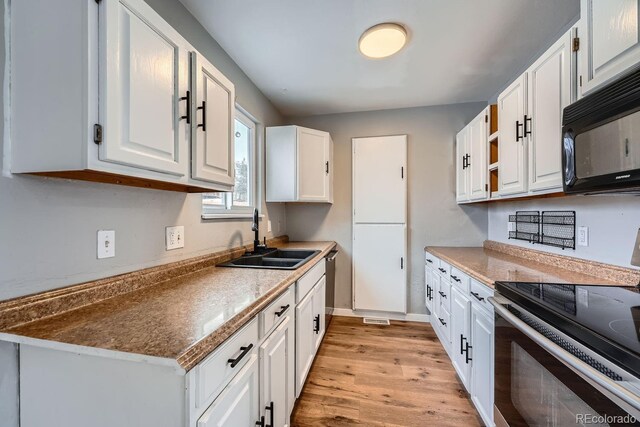 kitchen with electric stove, light wood-style flooring, white cabinets, a sink, and black microwave