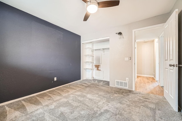 unfurnished bedroom with visible vents, a textured wall, ceiling fan, carpet, and a closet