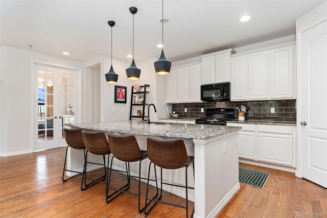 6046 Gilbert Way, Golden, CO 80403 - kitchen with black appliances, backsplash, a center island with sink, light wood-style flooring, and recessed lighting