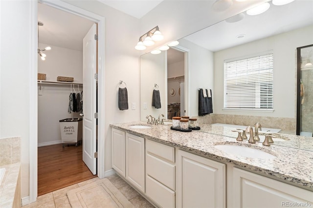 6046 Gilbert Way, Golden, CO 80403 - bathroom featuring double vanity, a garden tub, a spacious closet, tile patterned floors, and a shower with door