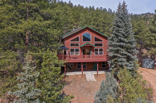 rear view of house with a wooded view and a wooden deck