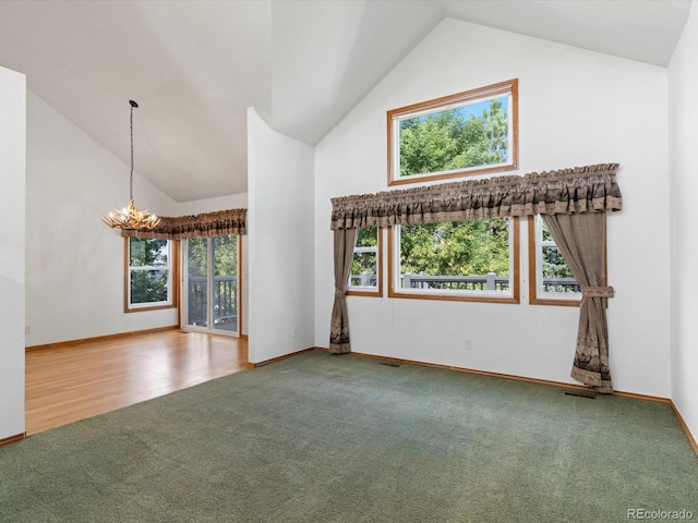 unfurnished living room featuring high vaulted ceiling, hardwood / wood-style flooring, and an inviting chandelier